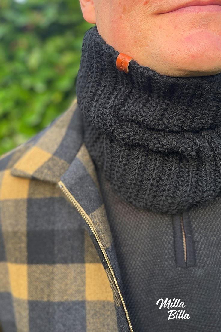 a close up of a person wearing a black sweater and a brown leather neck tie