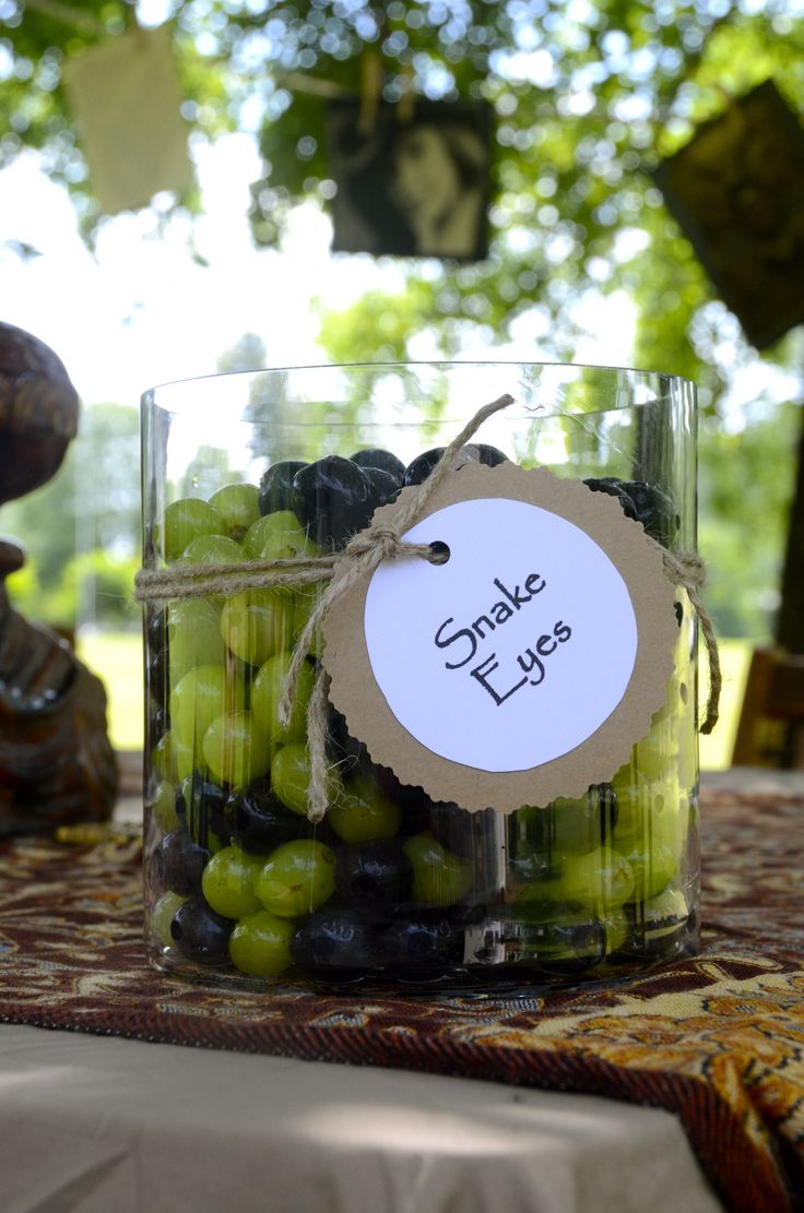 a jar filled with olives sitting on top of a table next to a tree