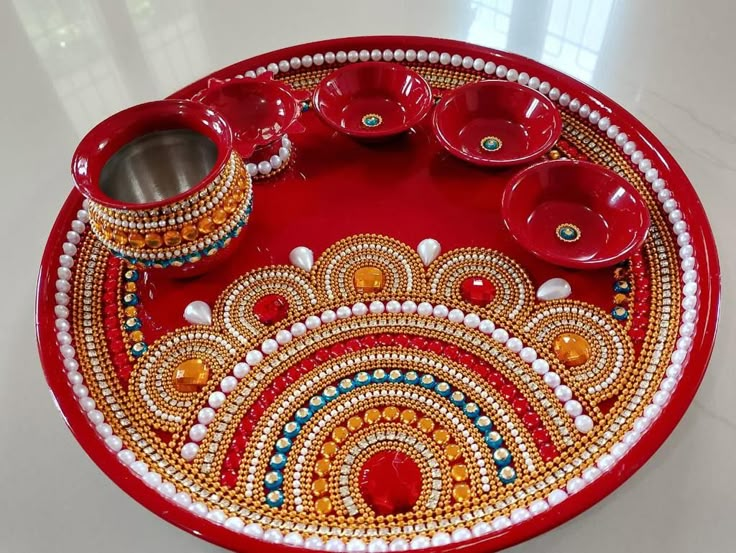 a red tray with two cups on it and some beads around the edges, sitting on a white table