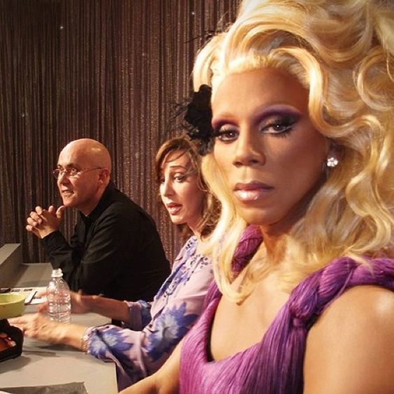 a woman with blonde hair sitting at a table in front of two men and one woman