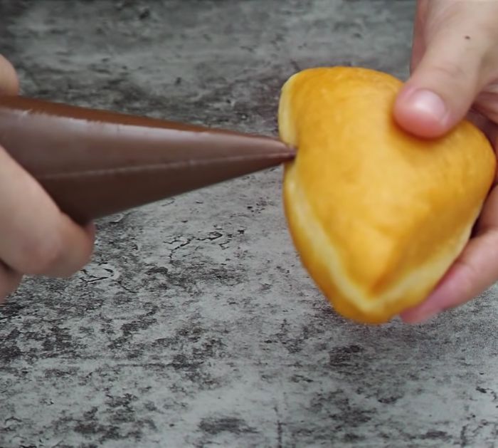 someone is cutting up a heart shaped pastry with a chocolate cone on the side and an orange slice in the middle