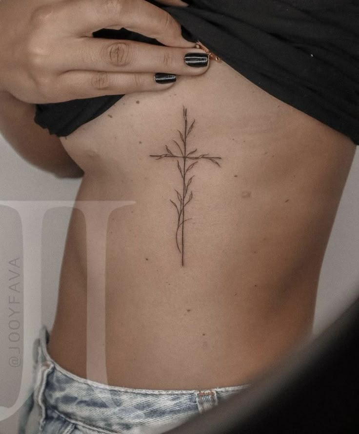 a cross tattoo on the back of a woman's rib - up stomach,