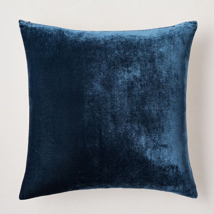 a blue velvet pillow on a white wall