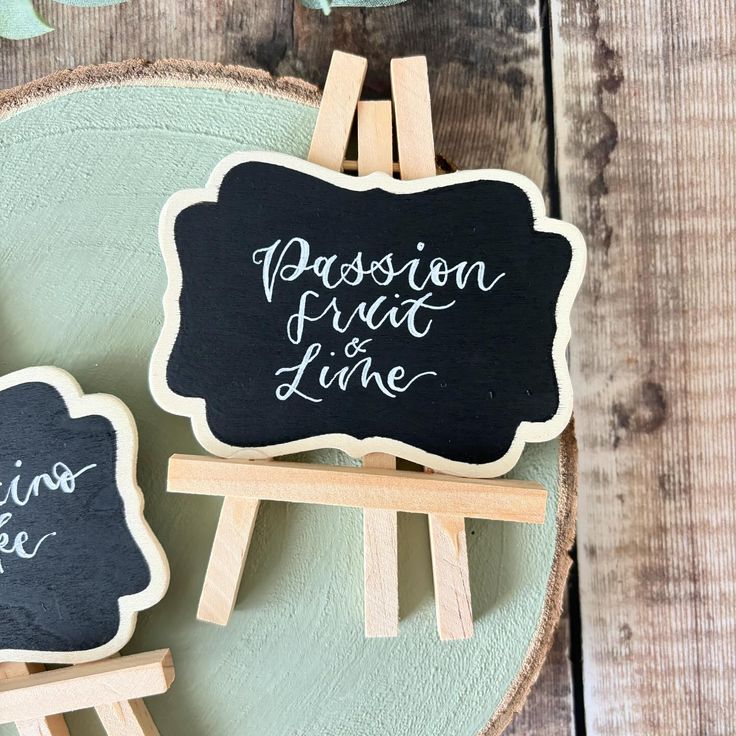 two wooden eases with chalkboard signs on them sitting on top of a table