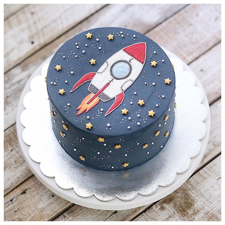 a blue cake with a rocket on it sitting on top of a white platter