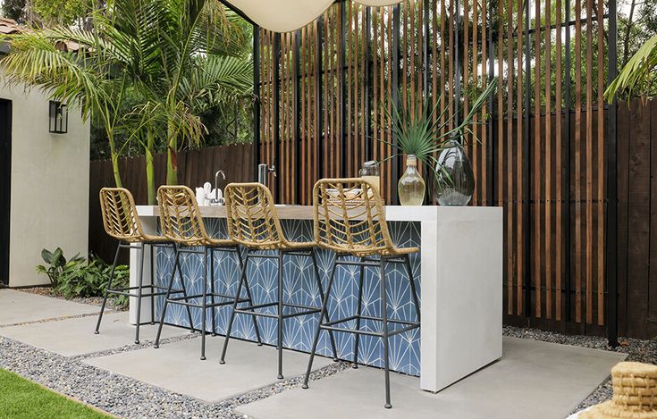 an outdoor bar with blue tile and gold barstools, surrounded by palm trees