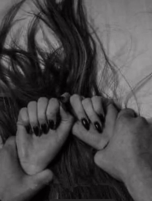 a woman laying on top of a bed with her hair blowing in the wind and nails sticking out