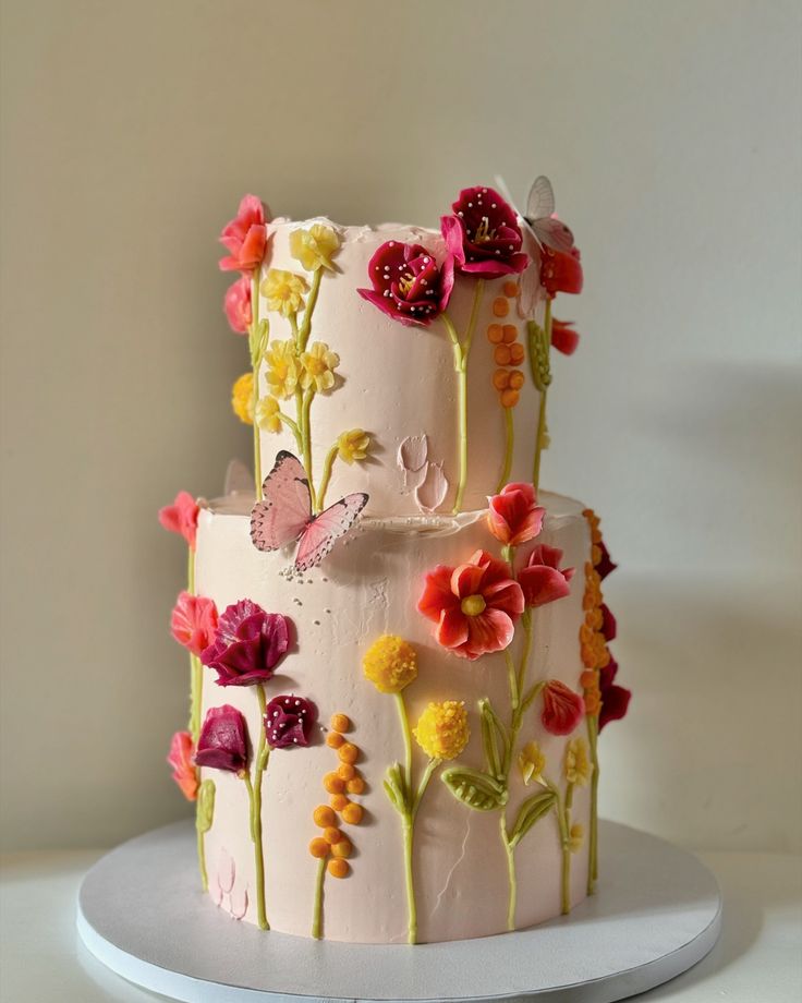 a three tiered cake decorated with flowers and butterflies