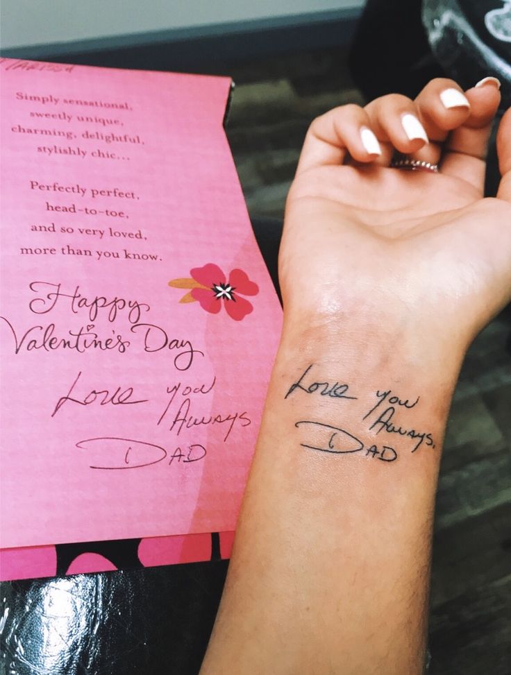 a woman's arm with a small tattoo on it and a pink card that says happy valentine's day