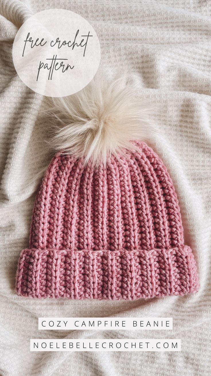 a pink knitted beanie with a white pom - pom on top