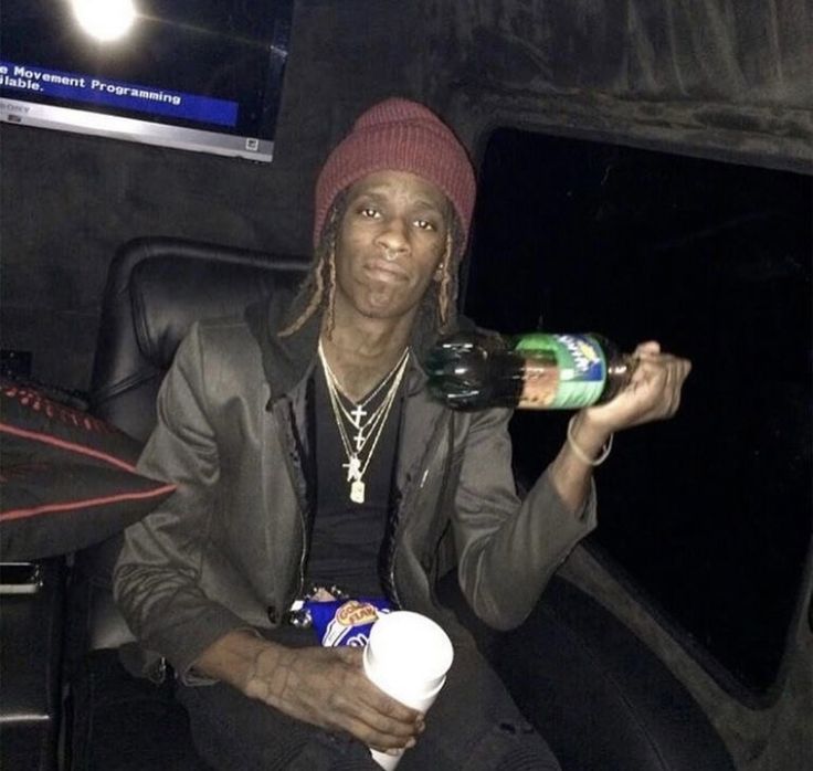 a man sitting in the back of a car drinking from a bottle and holding a cup