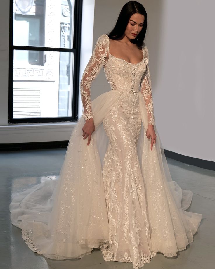 a woman in a wedding dress standing on a white floor next to a large window