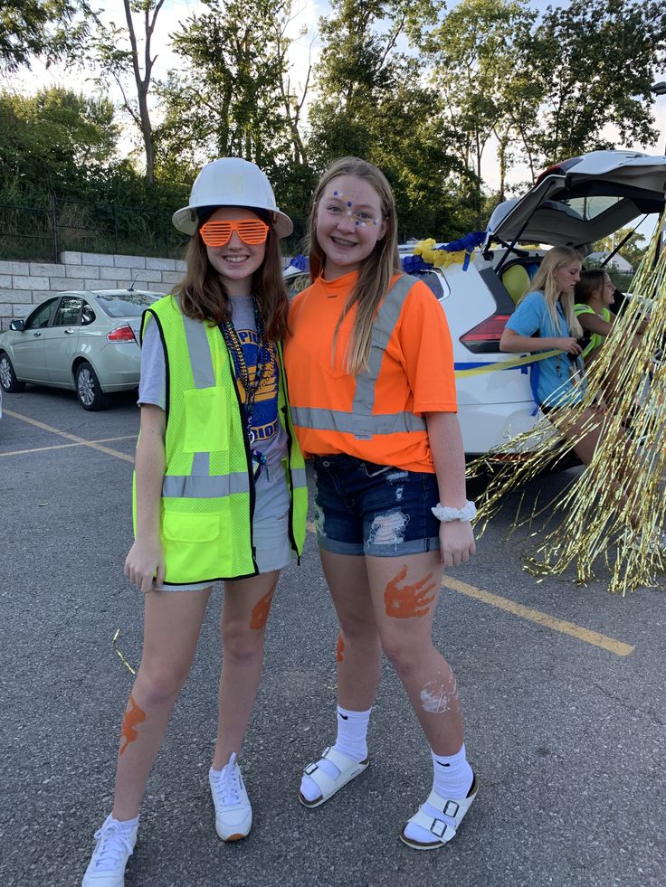 two young women standing next to each other wearing safety vests and orange reflective clothing