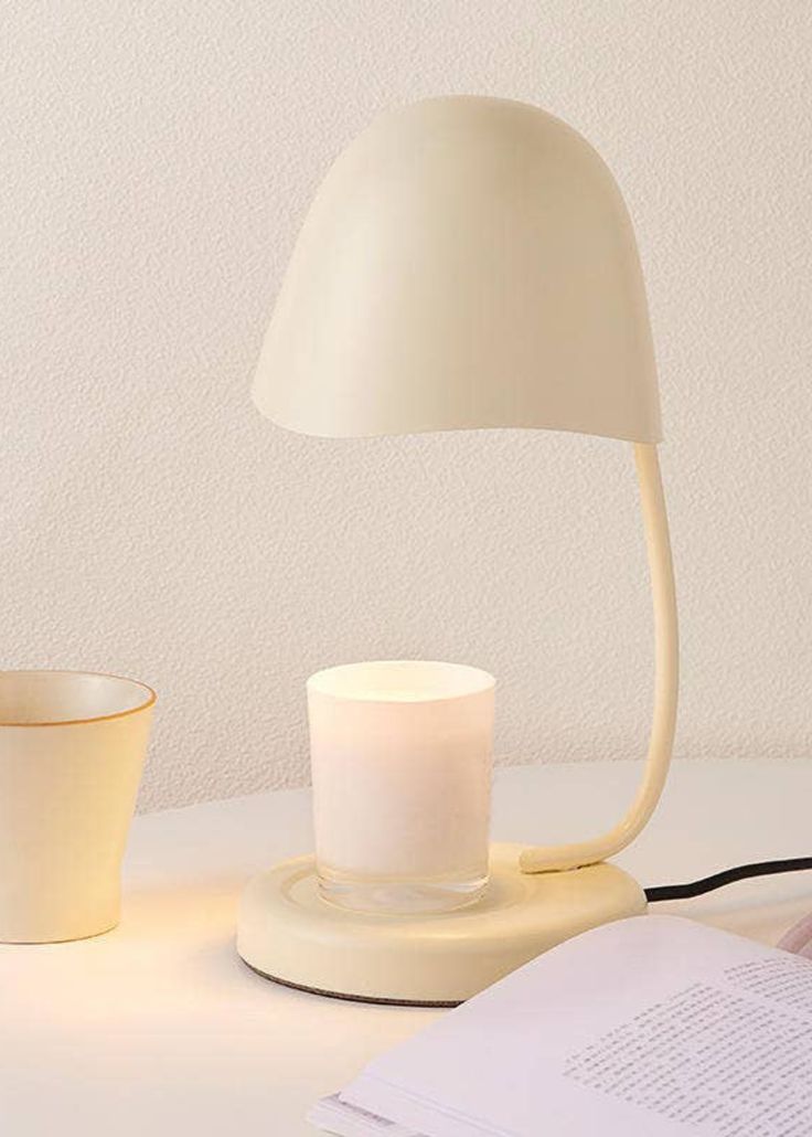 a white lamp sitting on top of a table next to a cup and saucer