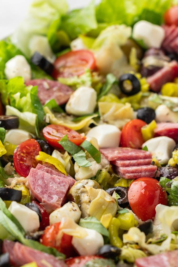 a salad with meat, olives, lettuce, tomatoes and other vegetables