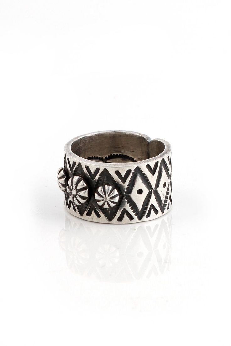 This J. Nez Sterling Silver Wide Ring is a ring you want to own. Three sterling silver rosettes decorate the top of the ring while the thick band has been deeply hand-stamped with diamond designs. The artist stamped the inside of the ring as well! The back has not been soldered to allow for adjustments. It has been oxidized to bring out detail and to give it a vintage look. This unique band adds a bit of interest to your outfit. The Navajo Nez family is well known for their excellent jewelry mak Bohemian Rings With Engraved Wide Band, Bohemian Wide Band Rings Engraved, Bohemian Wide Band Engraved Rings, Artisan Stamped Rings For Anniversary, Unique Wide Band Engraved Ring, Unique Engraved Wide Band Ring, Silver Engraved Wide Band Ring With Stamping, Silver Wide Band Engraved Ring, Unique Bands