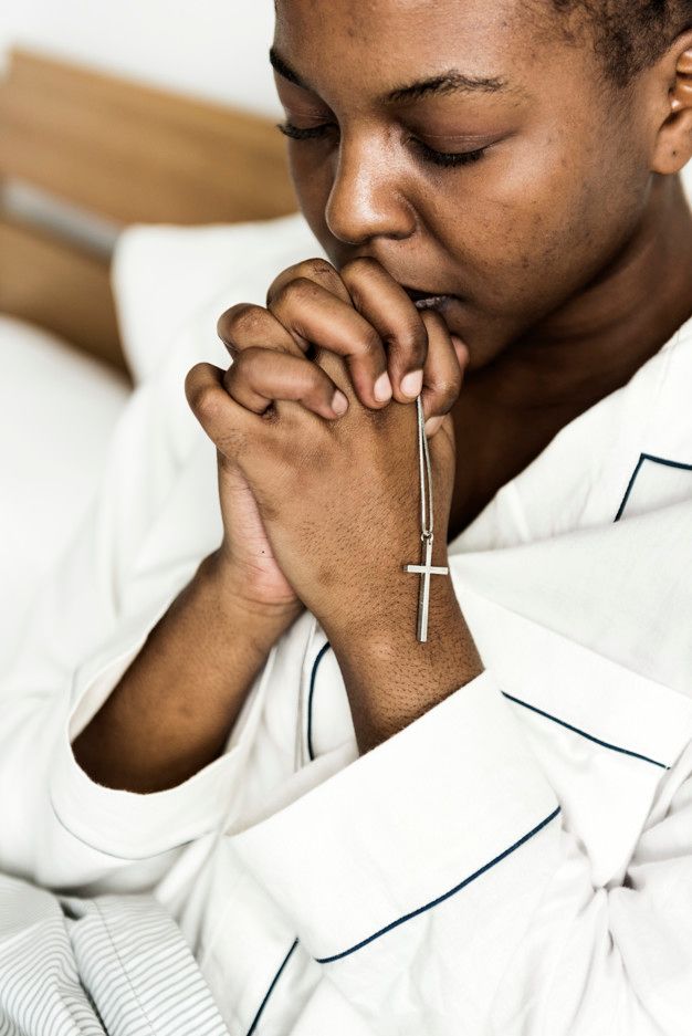 a woman with her hands clasped in front of her face and praying on the bed