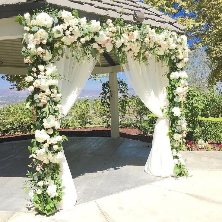 a gazebo decorated with white flowers and greenery