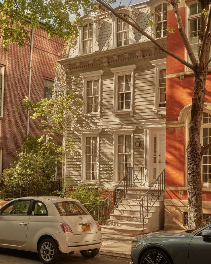 two cars are parked on the street in front of an old brick building with many windows