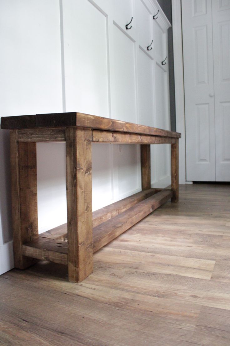 a wooden bench sitting on top of a hard wood floor next to a white door