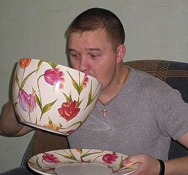 a man sitting in a chair drinking out of a tea cup and saucer that has flowers on it