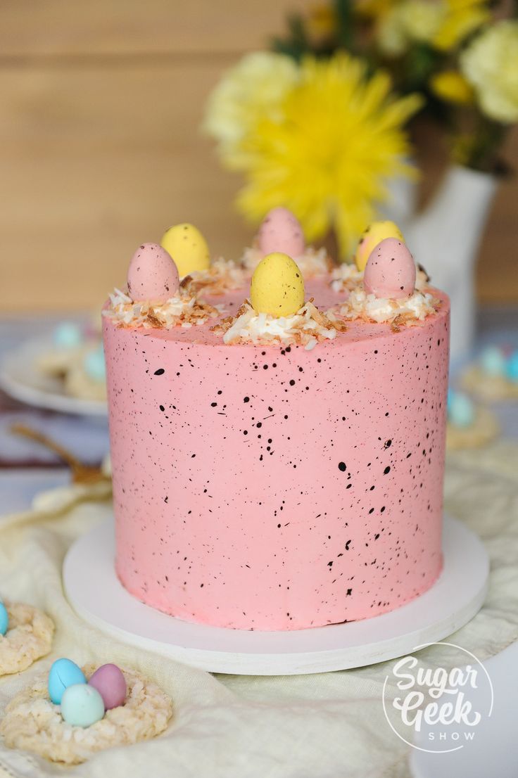 a pink cake with speckles and eggs on top