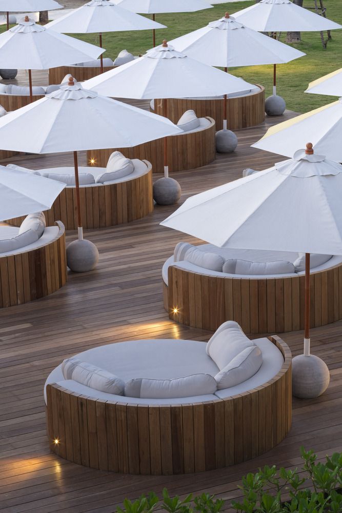 an outdoor seating area with umbrellas and lounge chairs on the deck at night time