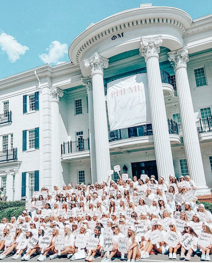 a group of people posing in front of a large white building with columns and pillars