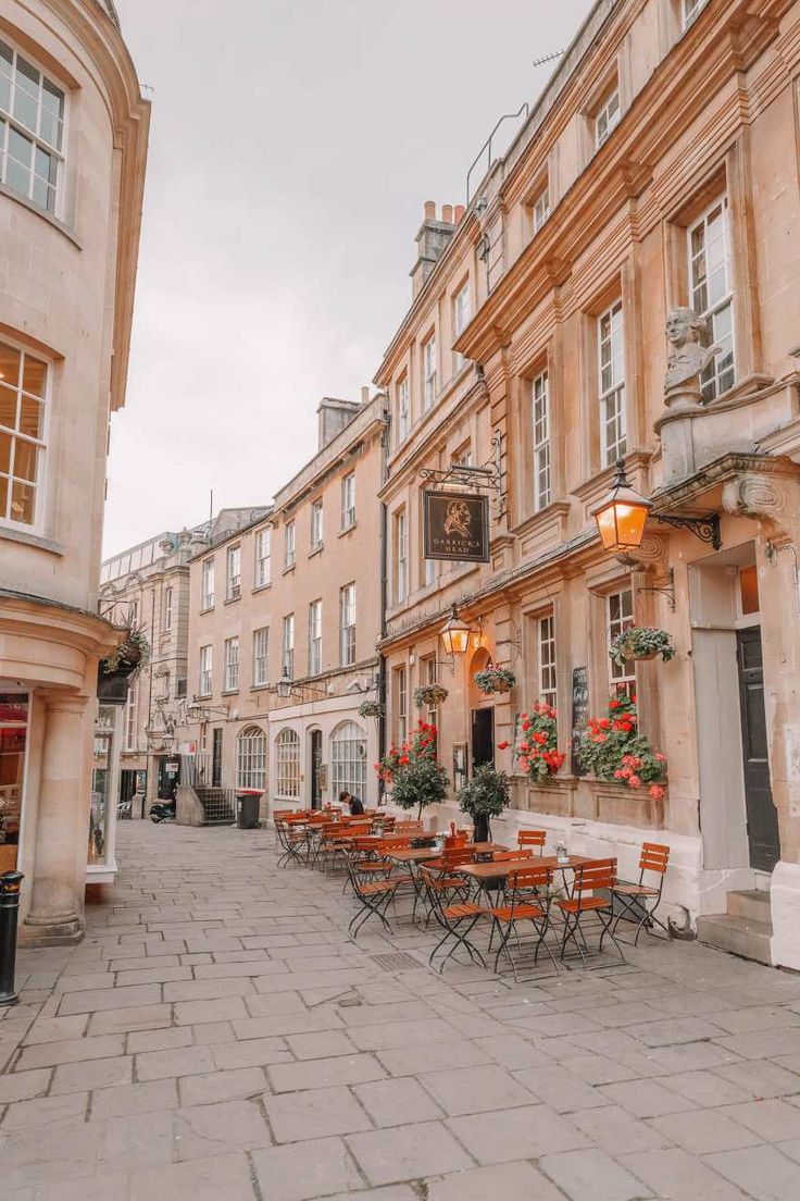 an empty street with tables and chairs on the sidewalk in front of some old buildings