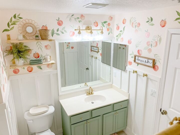 a bathroom with a sink, mirror and toilet in it's center wallpapered with peach flowers