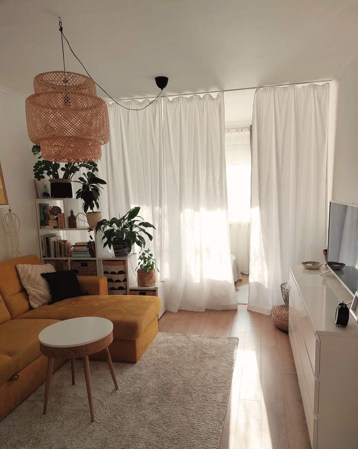 a living room filled with furniture and a large window covered in white drapes