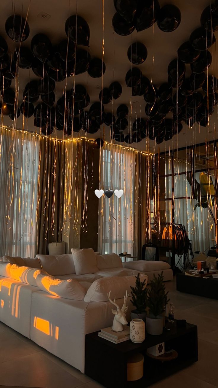 a living room filled with white couches and black balloons