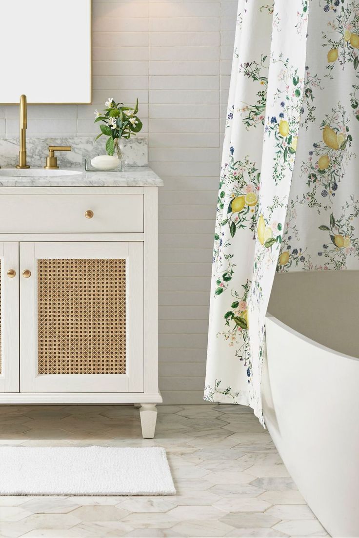 a bathroom with a sink, mirror and bathtub next to a shower curtain that has yellow flowers on it