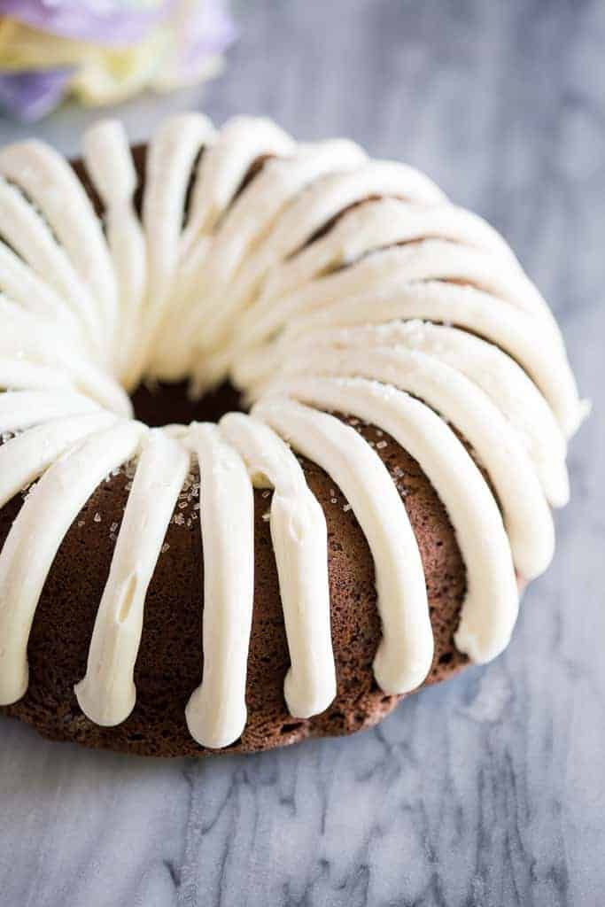 a chocolate bundt cake with white icing on a table