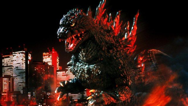 godzilla standing in front of city at night