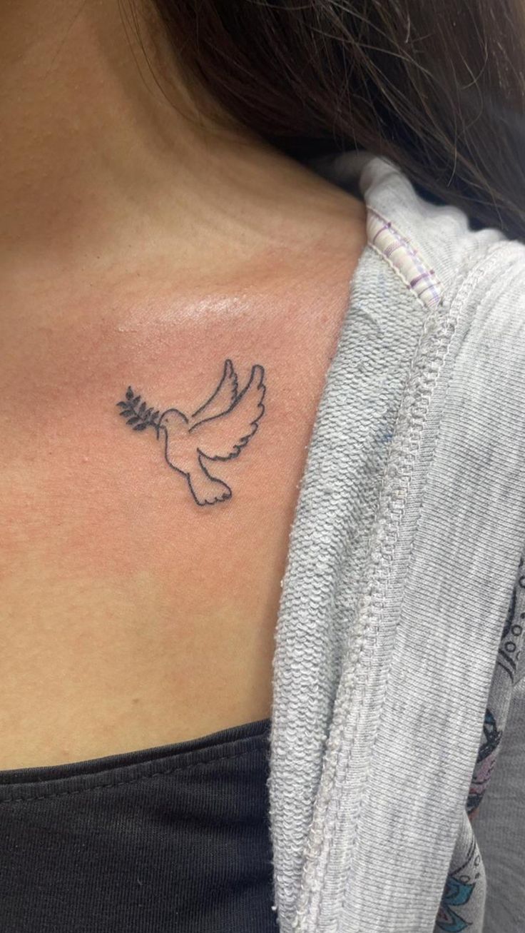 a woman's chest with a small tattoo of a bird on the left side