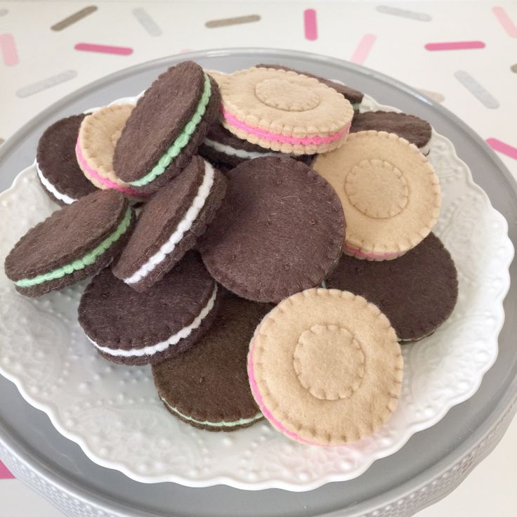 a plate full of cookies sitting on top of a white table cloth covered tablecloth