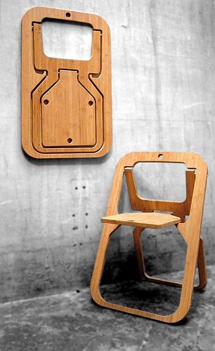 two wooden chairs sitting next to each other in front of a wall with a sign on it