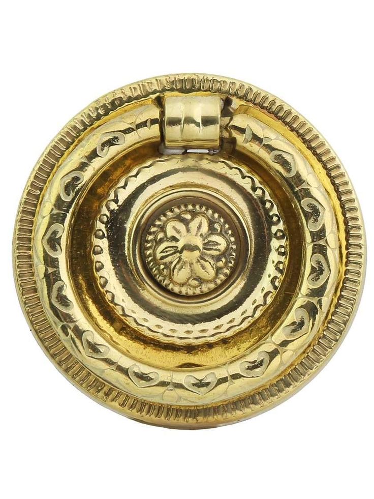 a gold colored metal object with an intricate design on the center and sides, against a white background