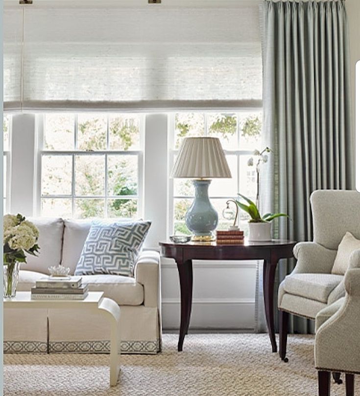 a living room filled with furniture and a window covered in blue drapes on the windowsill