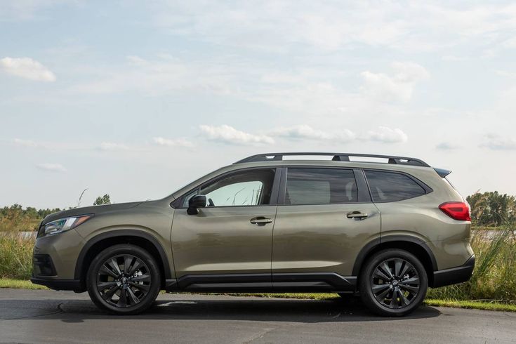 a silver subarunt is parked on the side of the road in front of some grass