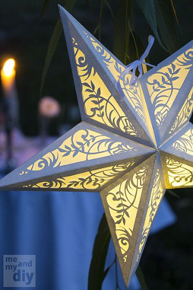 an ornament hanging from a tree with candles in the background at night time