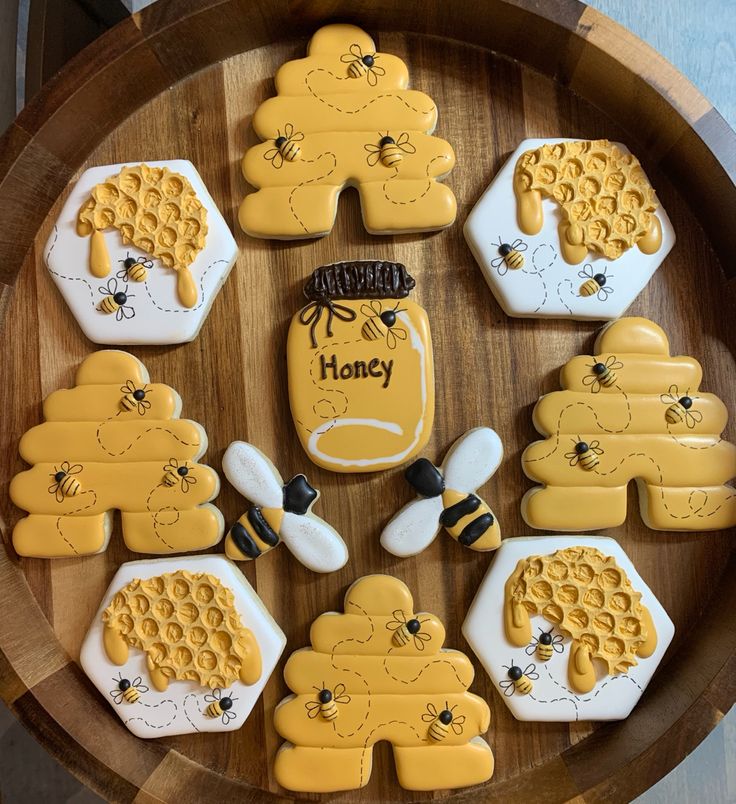 decorated cookies in the shape of bees and honeycombs on a wooden platter