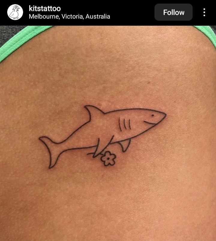 a small shark tattoo on the back of a woman's stomach