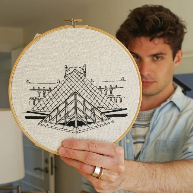 a man holding up a cross - stitch pattern in front of his face and hand