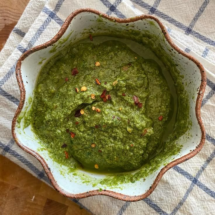 a bowl filled with green pesto on top of a table