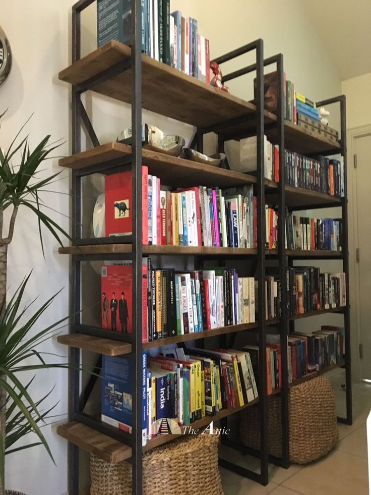 a bookshelf filled with lots of books next to a potted plant