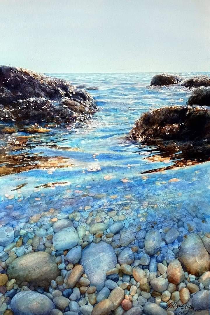 the water is crystal blue and clear with rocks on both sides in the foreground