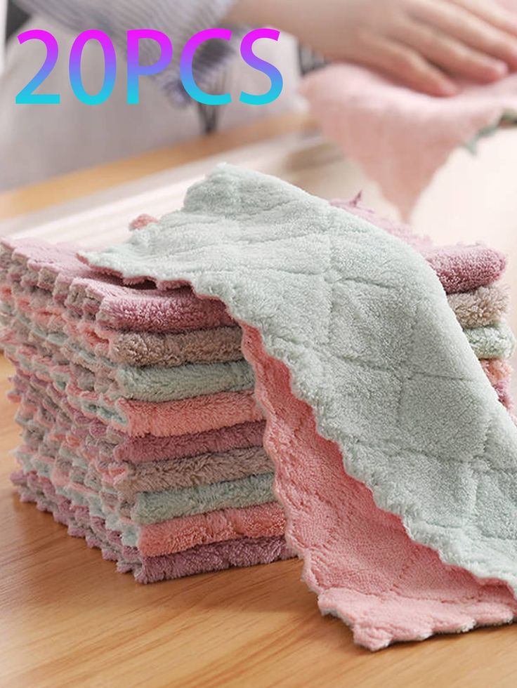 a stack of folded towels sitting on top of a wooden table next to a person