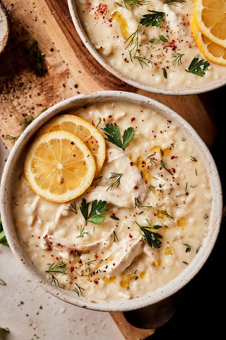 two bowls filled with oatmeal topped with lemon slices and garnished with herbs